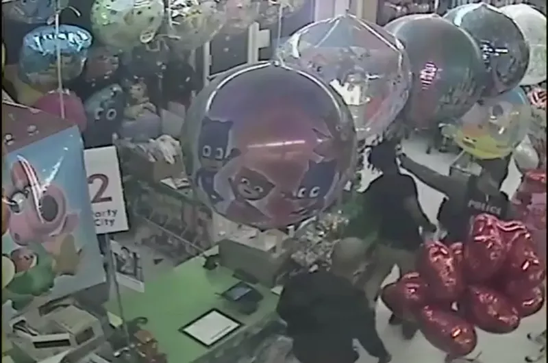 Image: Surveillance footage shows a police officer (right foreground) smacking Bill Alcius in the head.