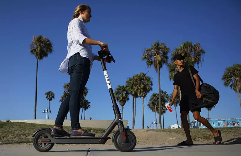Image: A woman drives an electric scooter on Venice Beach in Los Angeles.
