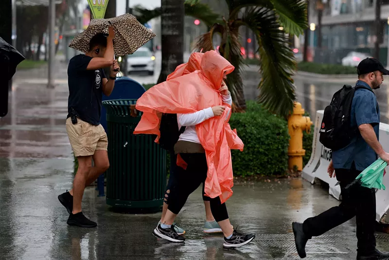 Image: Pedestrians try to stay dry as rain inundates the area on November 15, 2023, in Miami Beach, Florida.