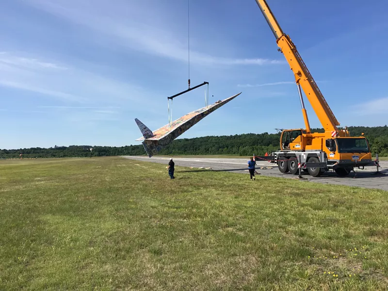 Image: Beck's giant paper airplane, carried by a crane.