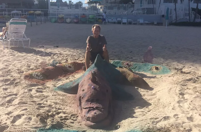 Image: Rich Dutoko atop one of his sand sculptures.