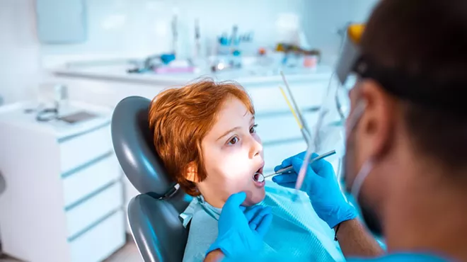 Young boy in a dentists office having work done on his teeth by a male dentist
